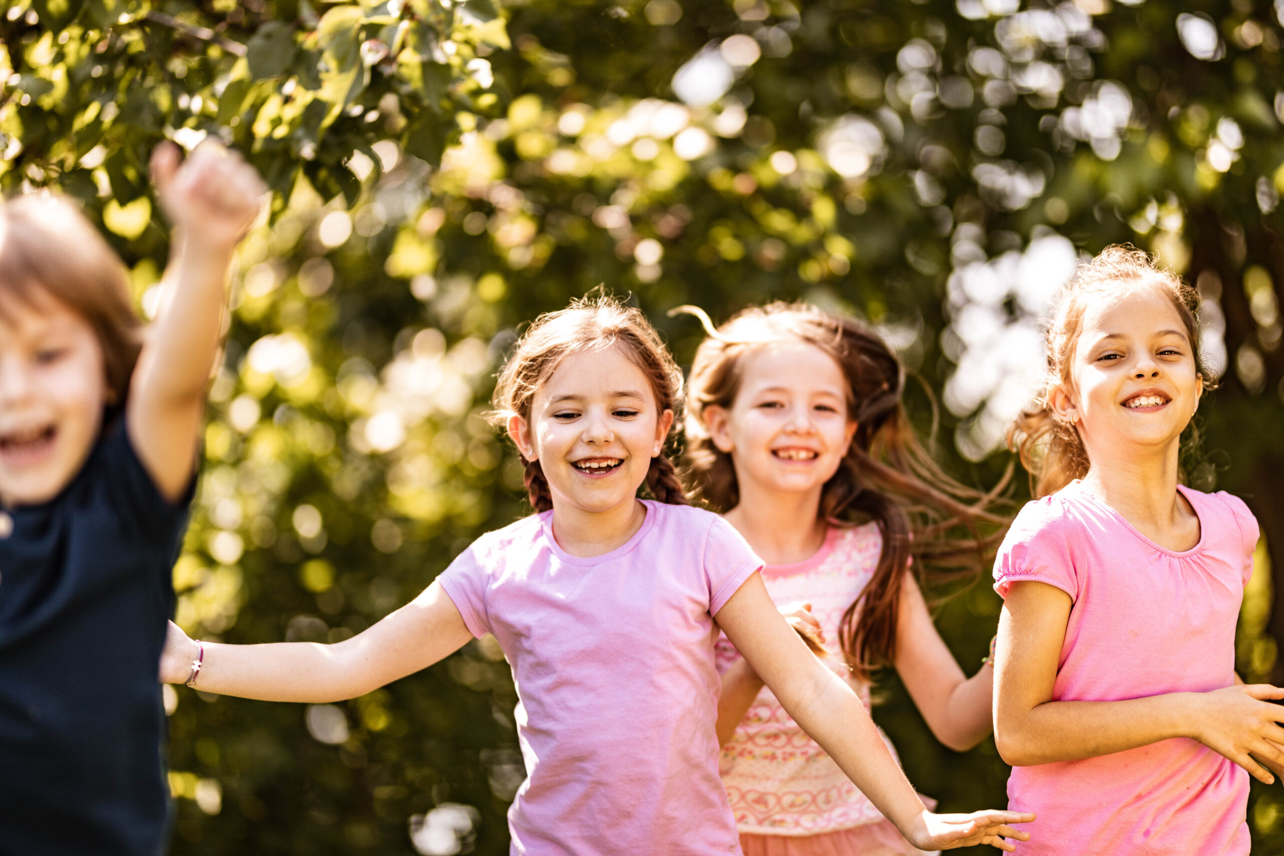 Group of happy kids having fun while running in springtime at the park. Copy space.